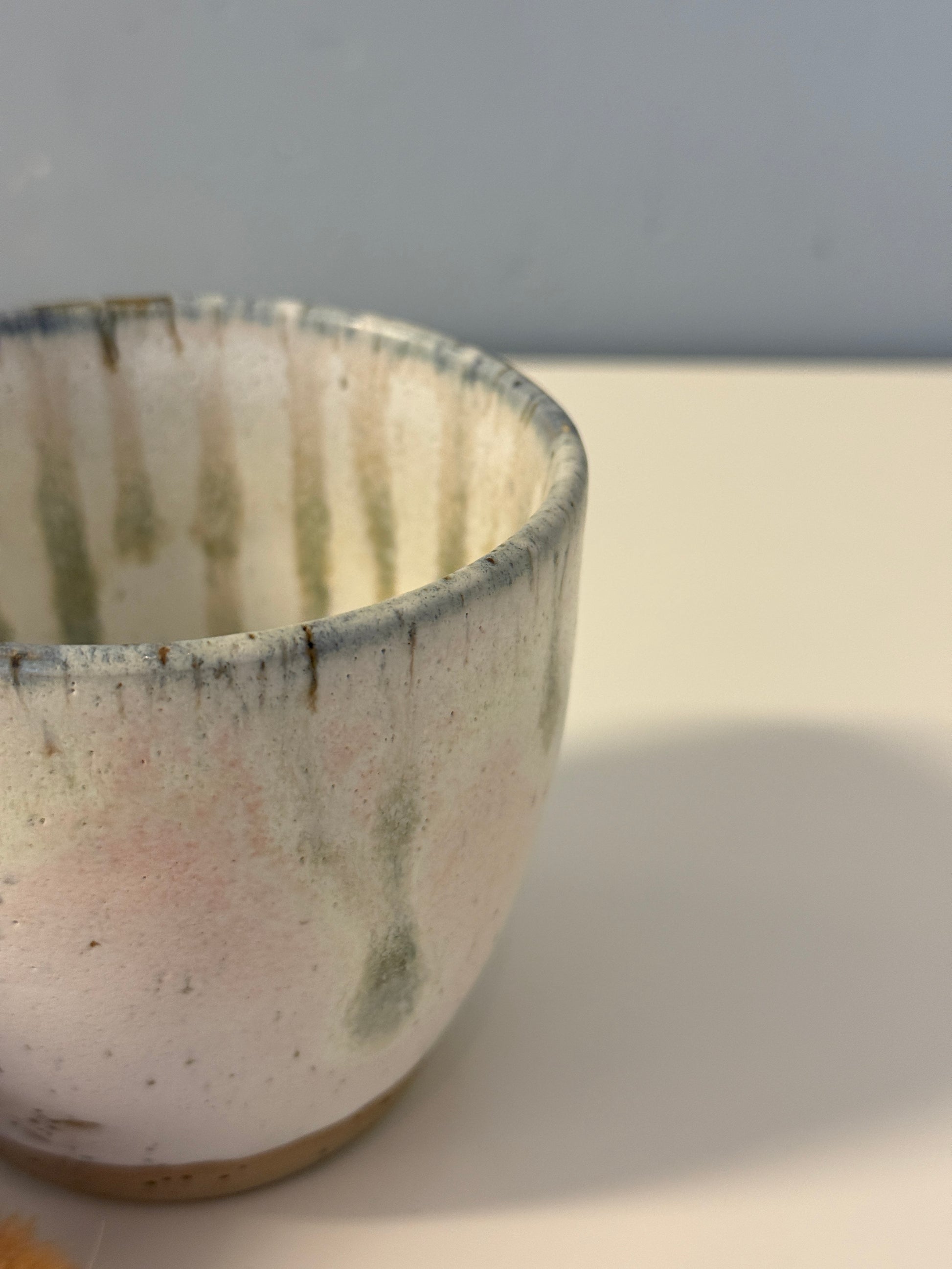 Handgemachte Becher glasiert in weiß mit blauen Tropfen