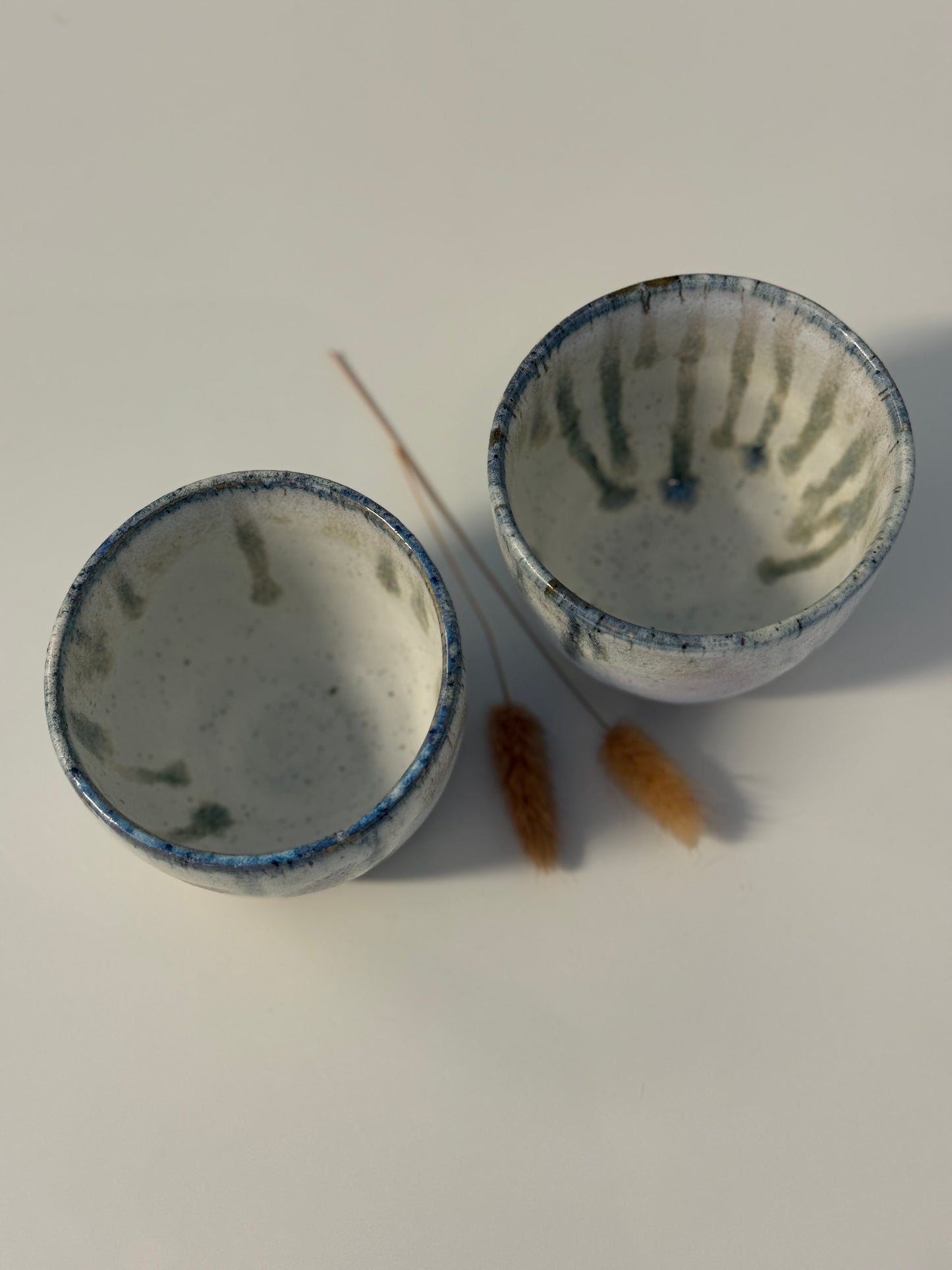 Handgemachte Becher glasiert in weiß mit blauen Tropfen