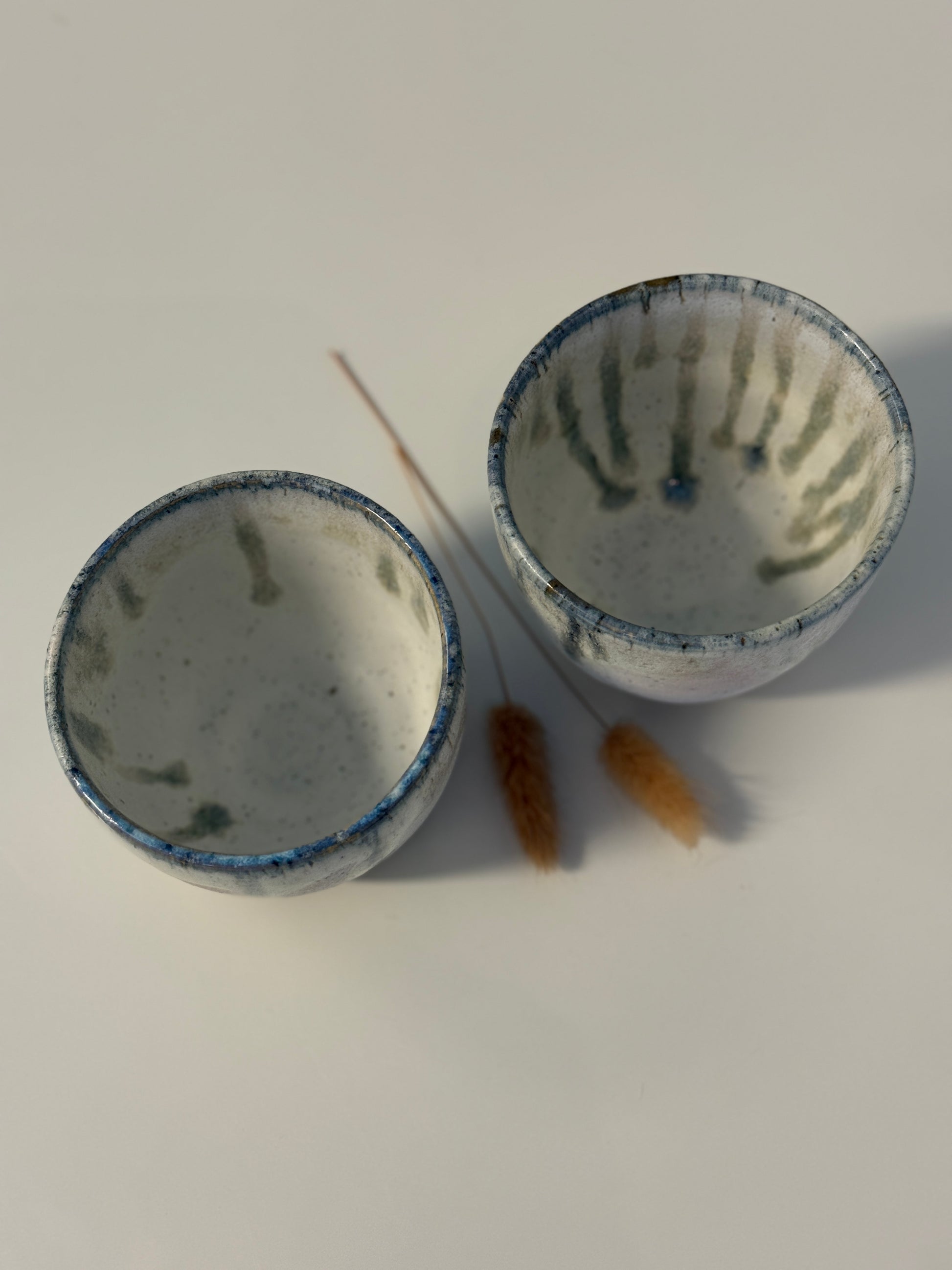 Handgemachte Becher glasiert in weiß mit blauen Tropfen