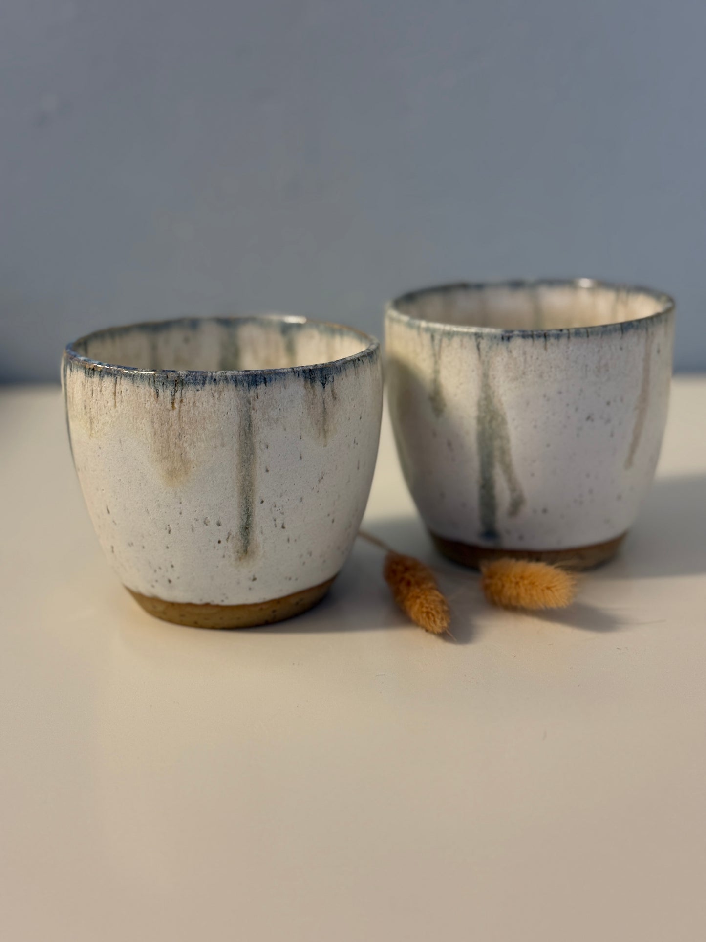 Handgemachte Becher glasiert in weiß mit blauen Tropfen
