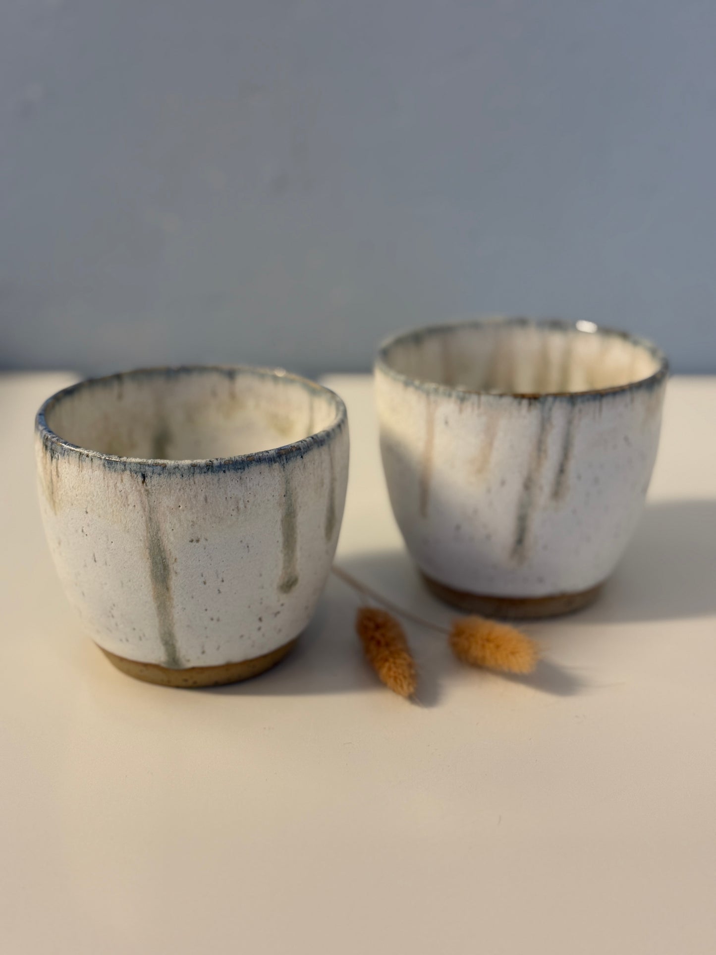Handgemachte Becher glasiert in weiß mit blauen Tropfen