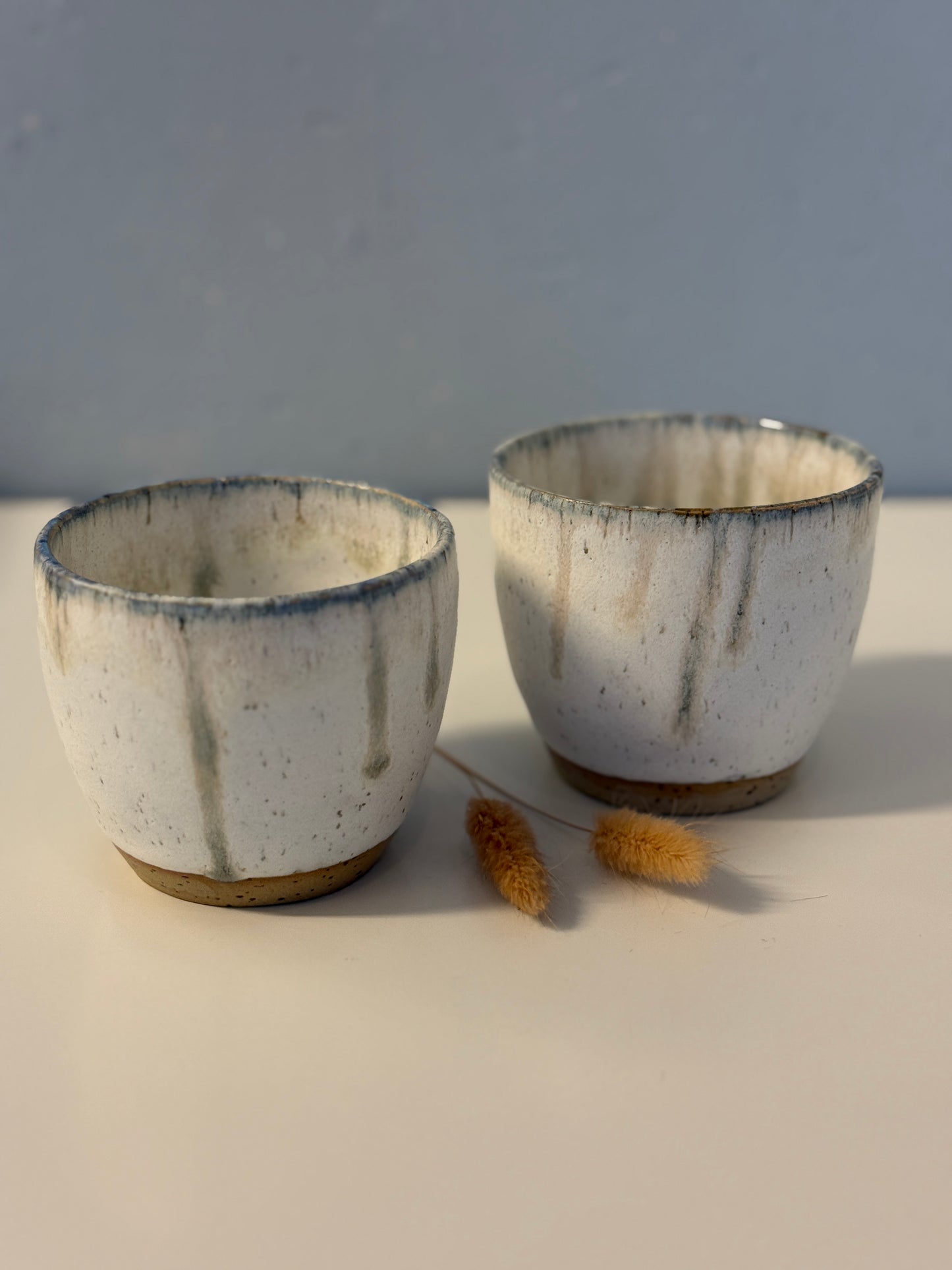 Handgemachte Becher glasiert in weiß mit blauen Tropfen
