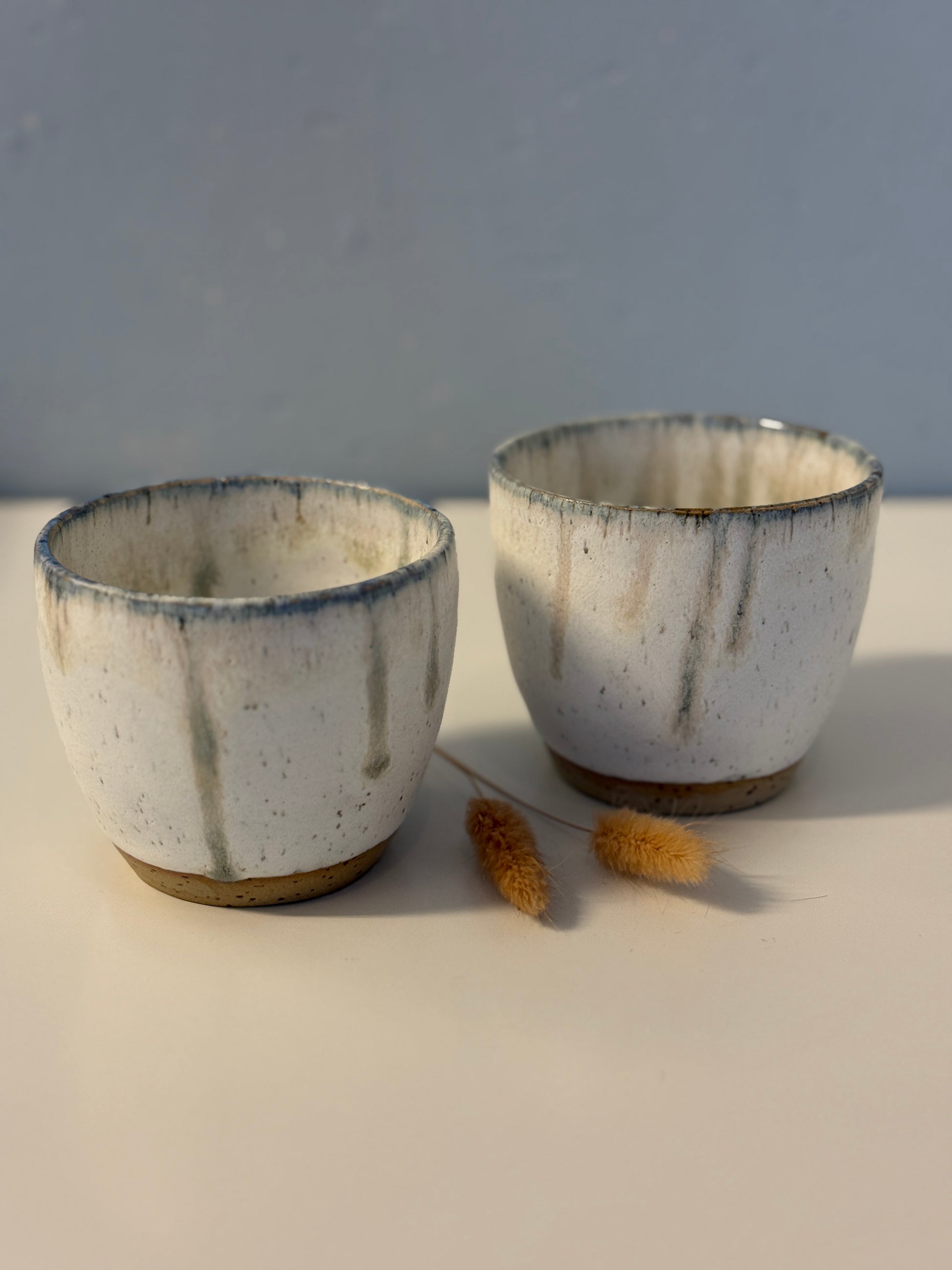Handgemachte Becher glasiert in weiß mit blauen Tropfen