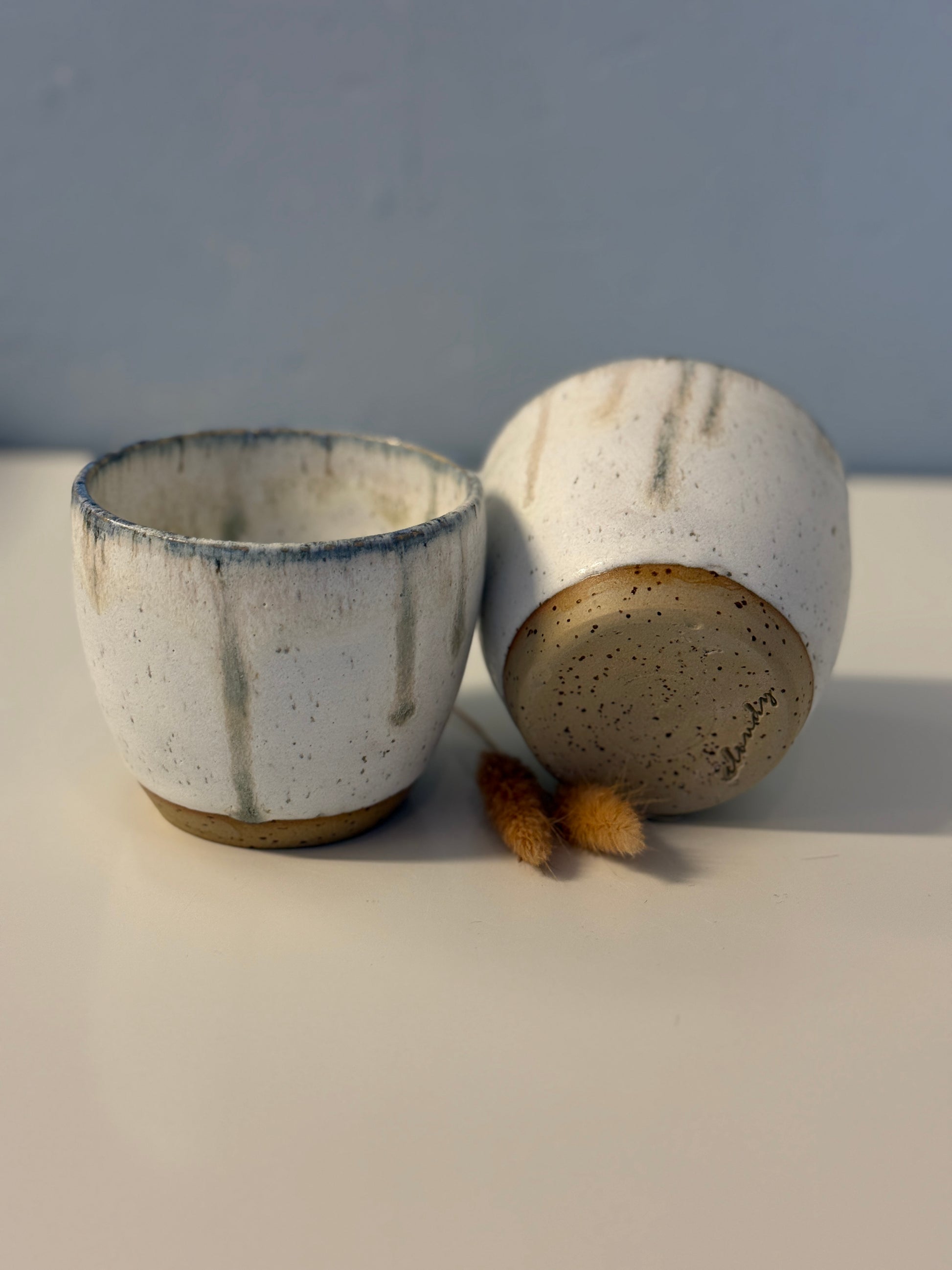 Handgemachte Becher glasiert in weiß mit blauen Tropfen