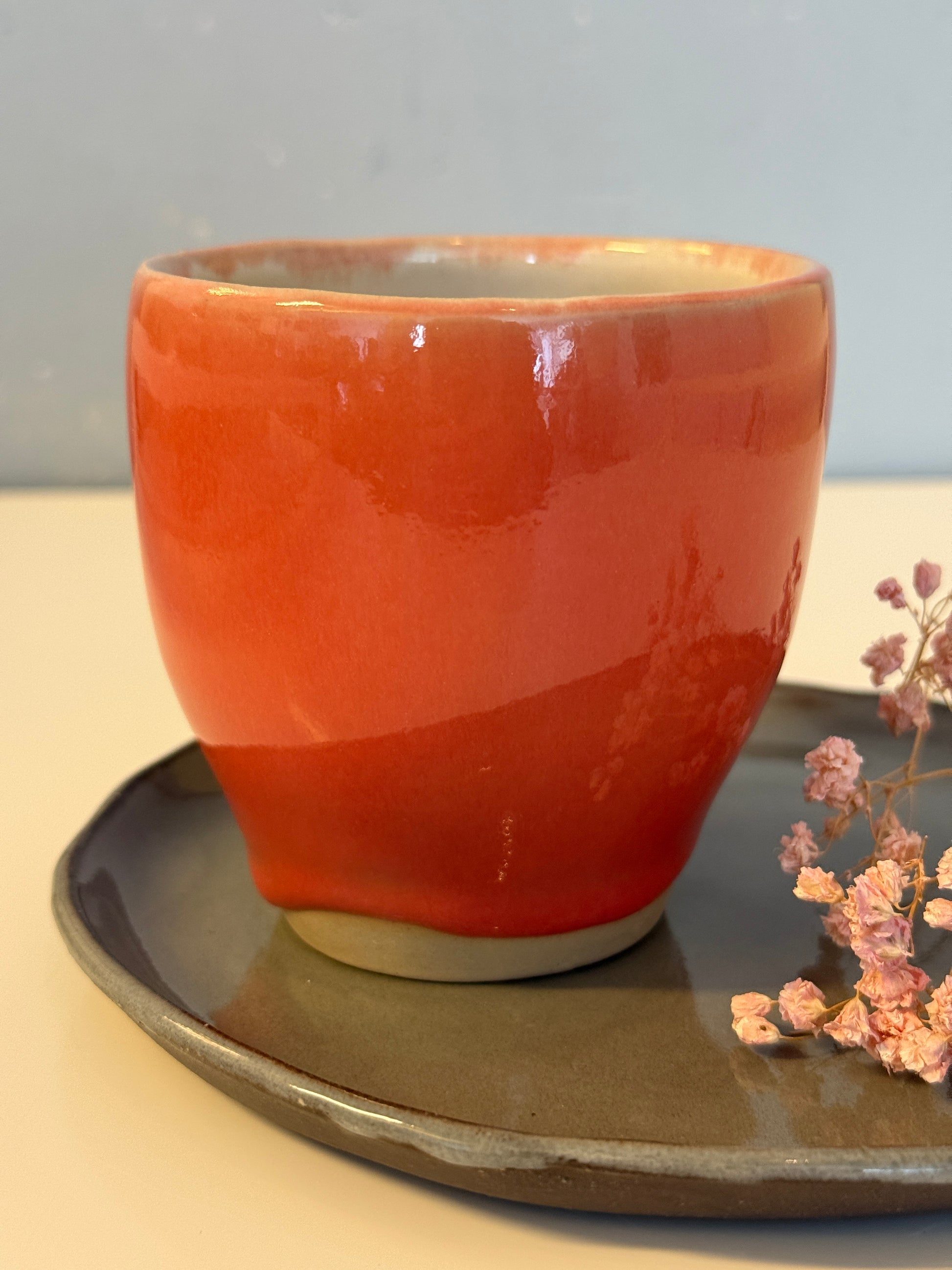 Becher glasiert in Perlrosa auf hellem Ton und einen kleinen Untersetzteller glaseir in grau auf schwarzem Ton.&nbsp;